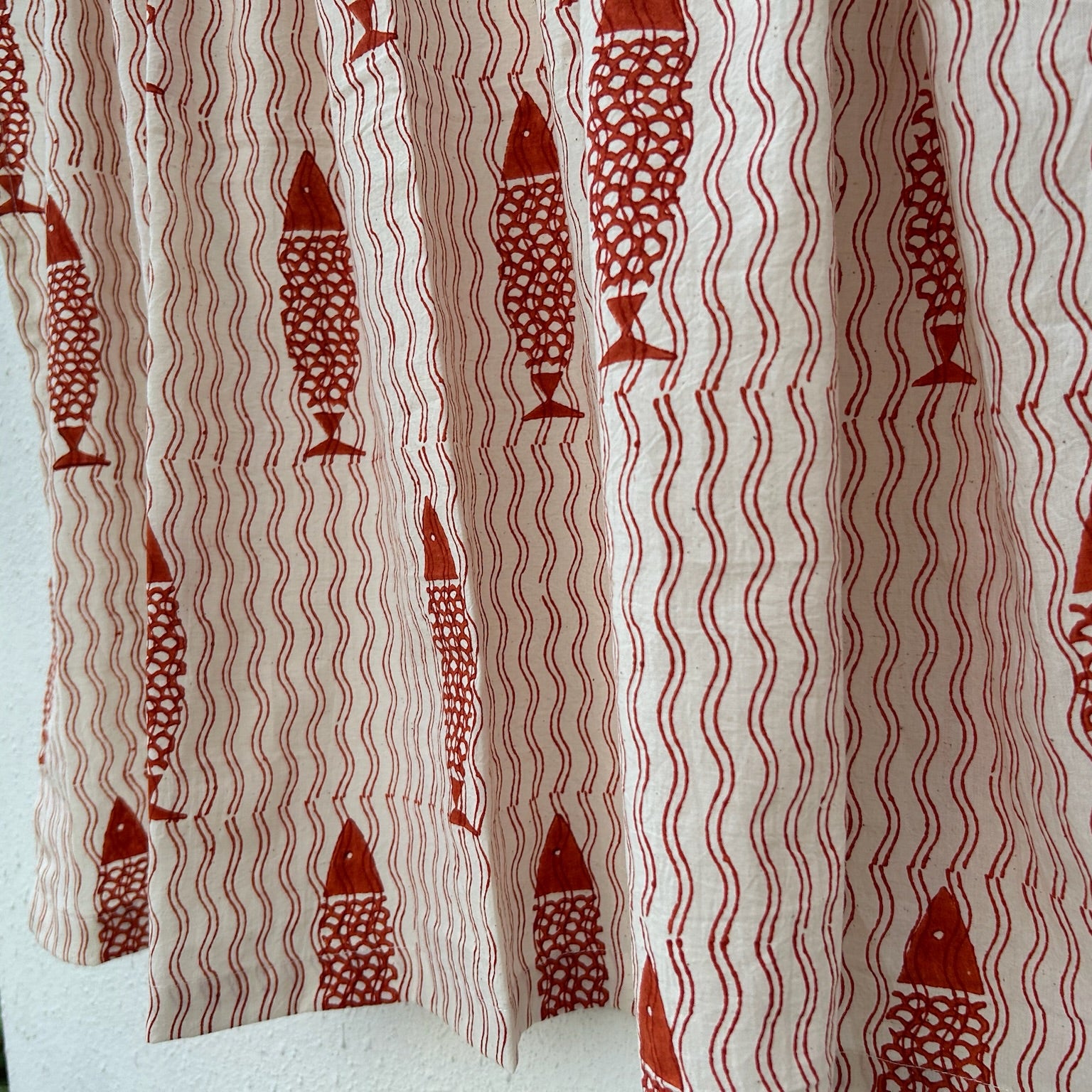 Curtain with red fish and wavy line pattern on a white background