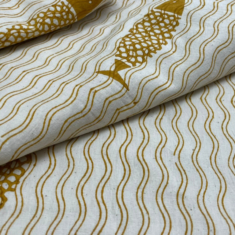 Close-up of fabric with gold wave and fish pattern on a white background