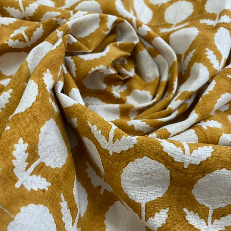 Close-up of fabric with white floral pattern on mustard yellow background
