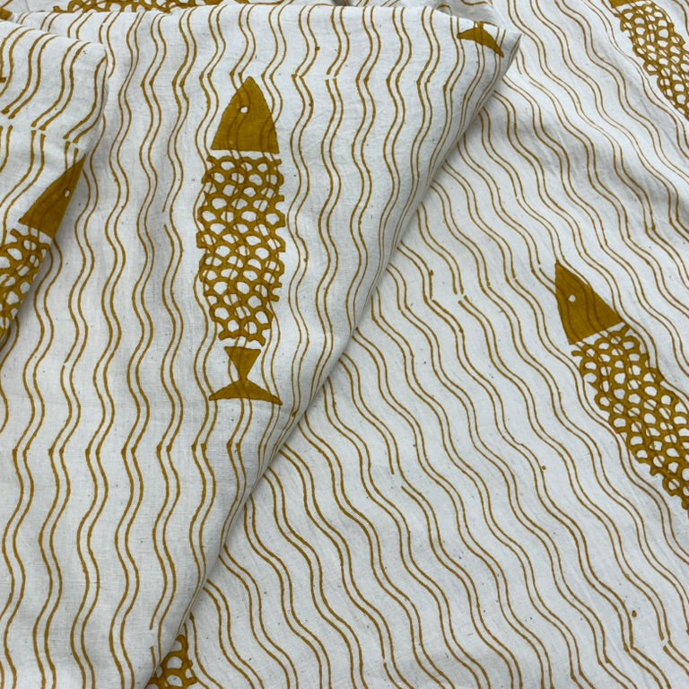 Fabric with gold fish and wavy line pattern on a white background