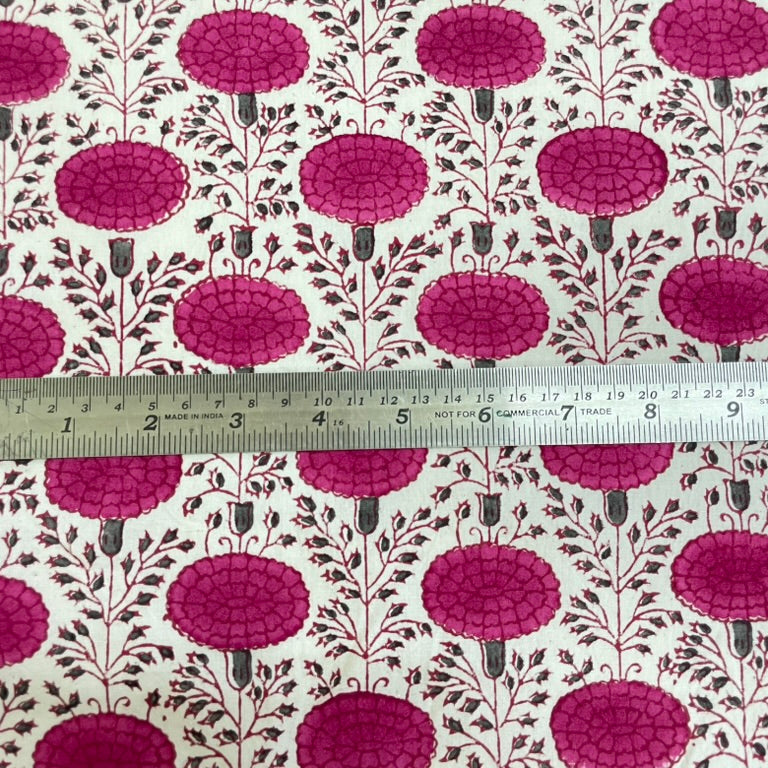 Fabric with pink floral pattern and a ruler for scale on a white background