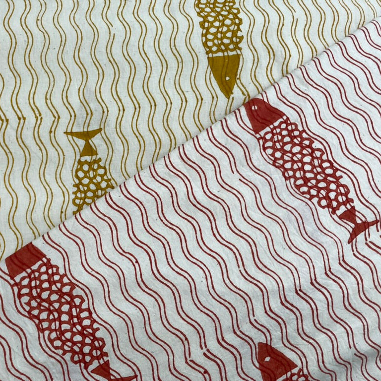 Fabric with fish and wave pattern in gold and red on a white background