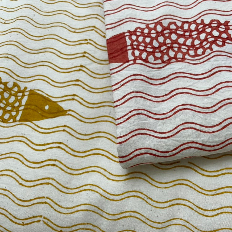 Textile with fish and wave patterns in red and gold on a white background