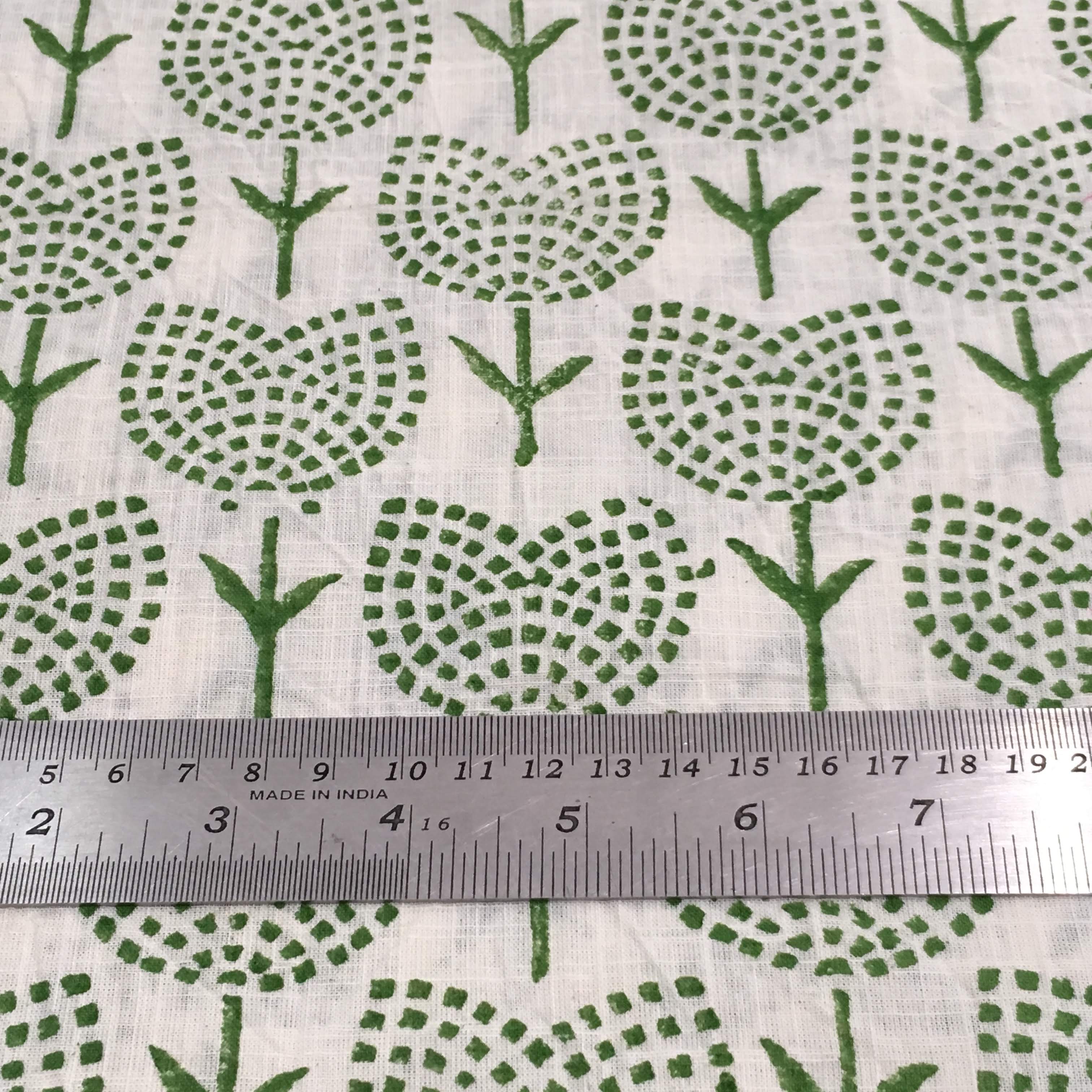 Green floral pattern on white fabric with a ruler for scale