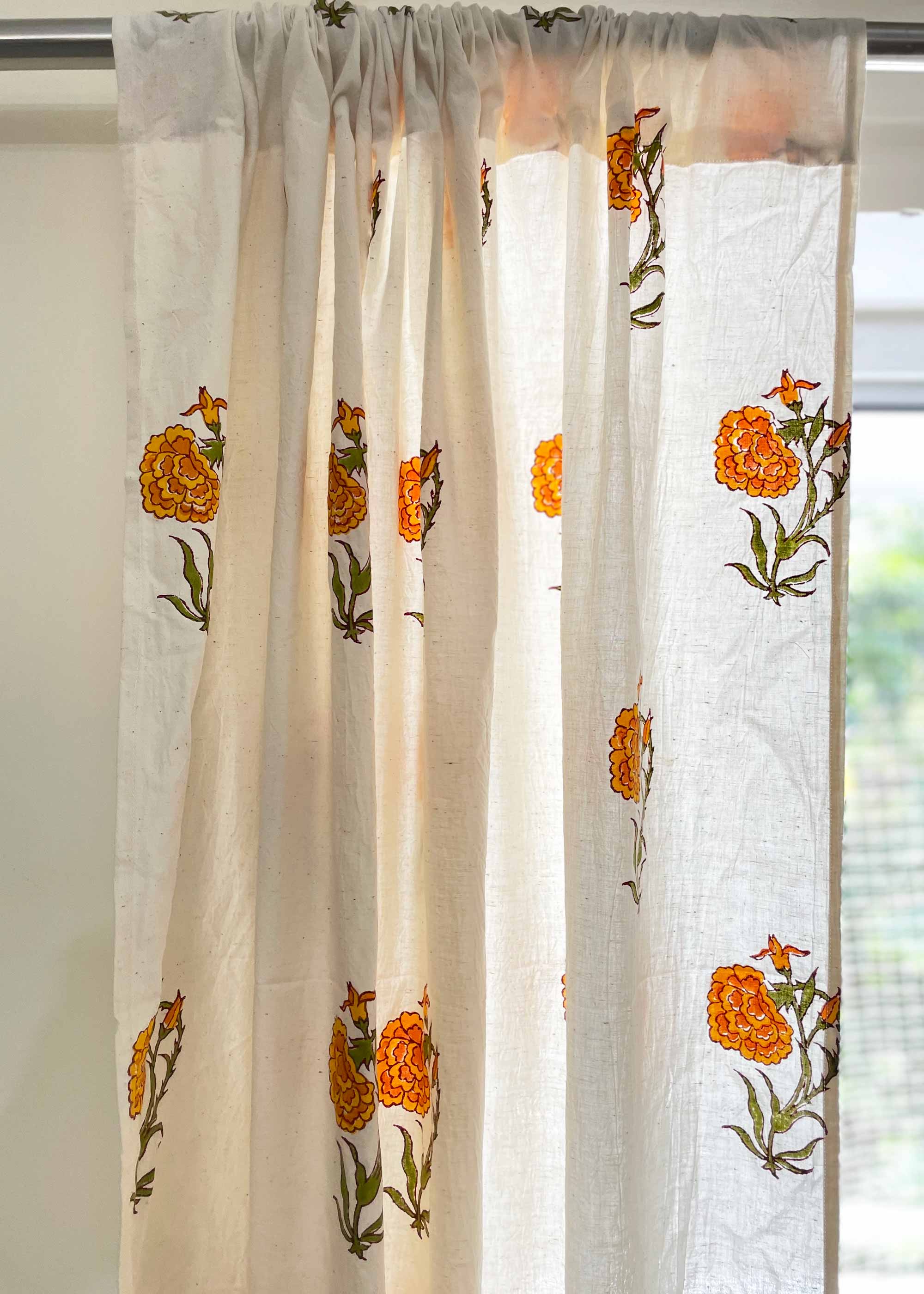 Sheer curtain with floral embroidery in orange and green on a white background