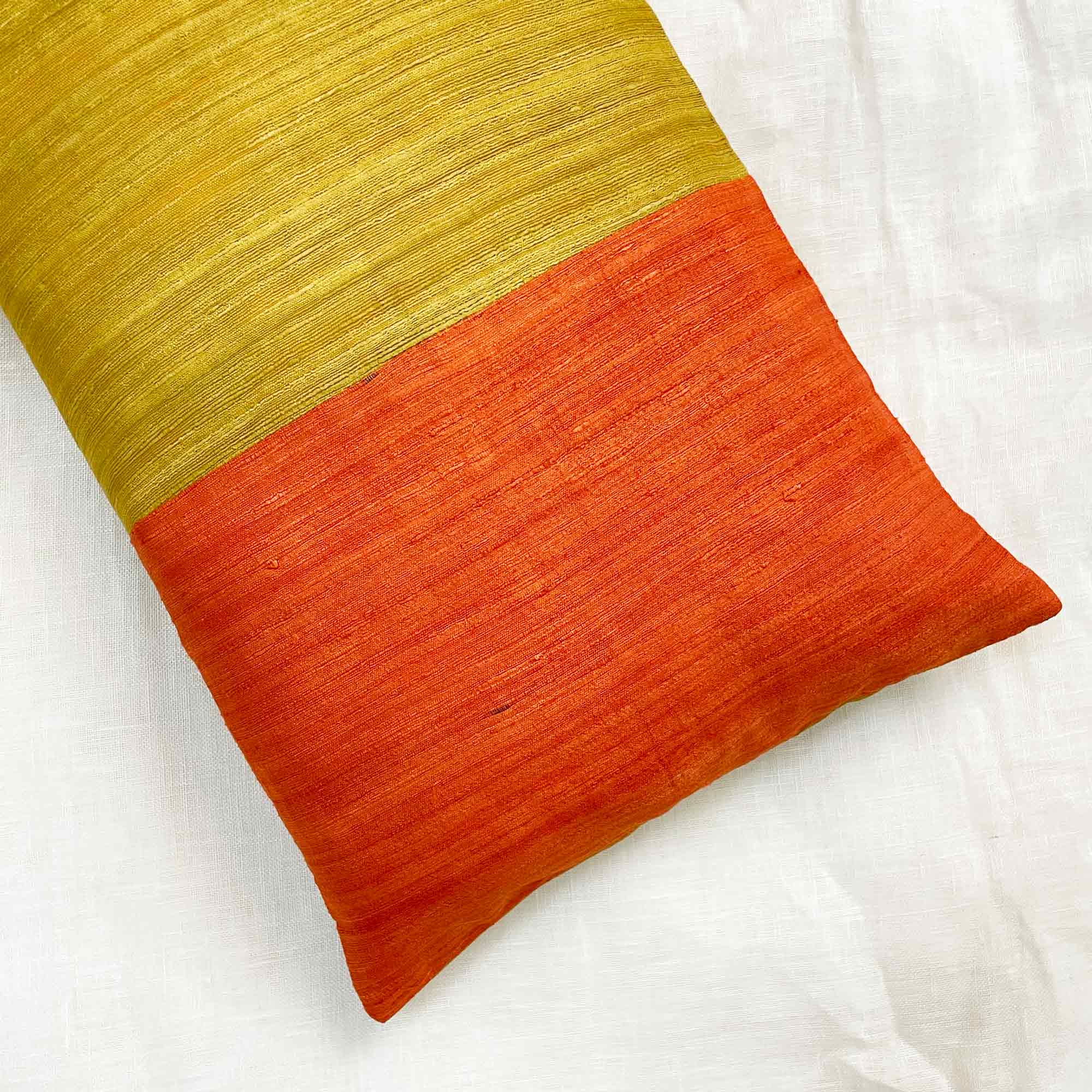 Detail view of bold colorblock tussar silk pillow cover showing organic texture and earthy tones.