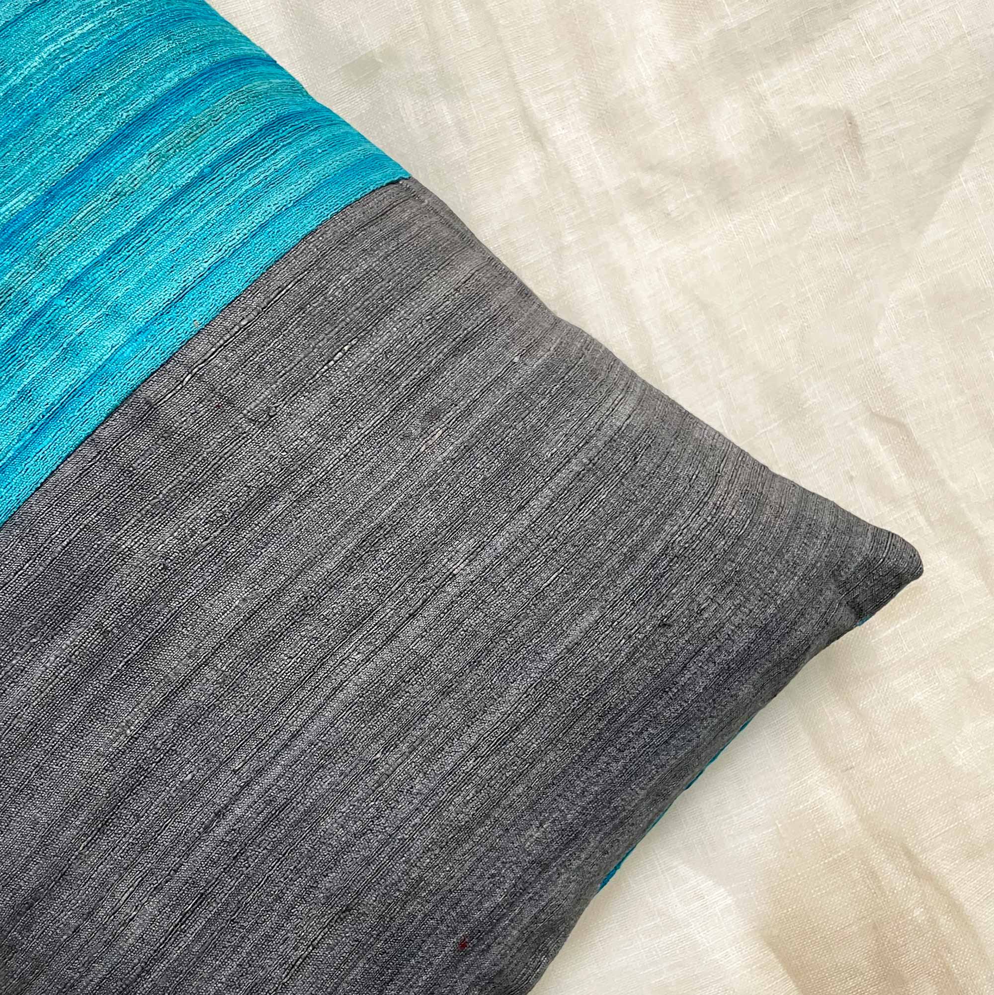 Close-up of grey and teal colorblock silk pillow cover highlighting silk texture and tonal contrast.