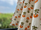 Close-up of fabric with orange and green pattern against a blurred outdoor background