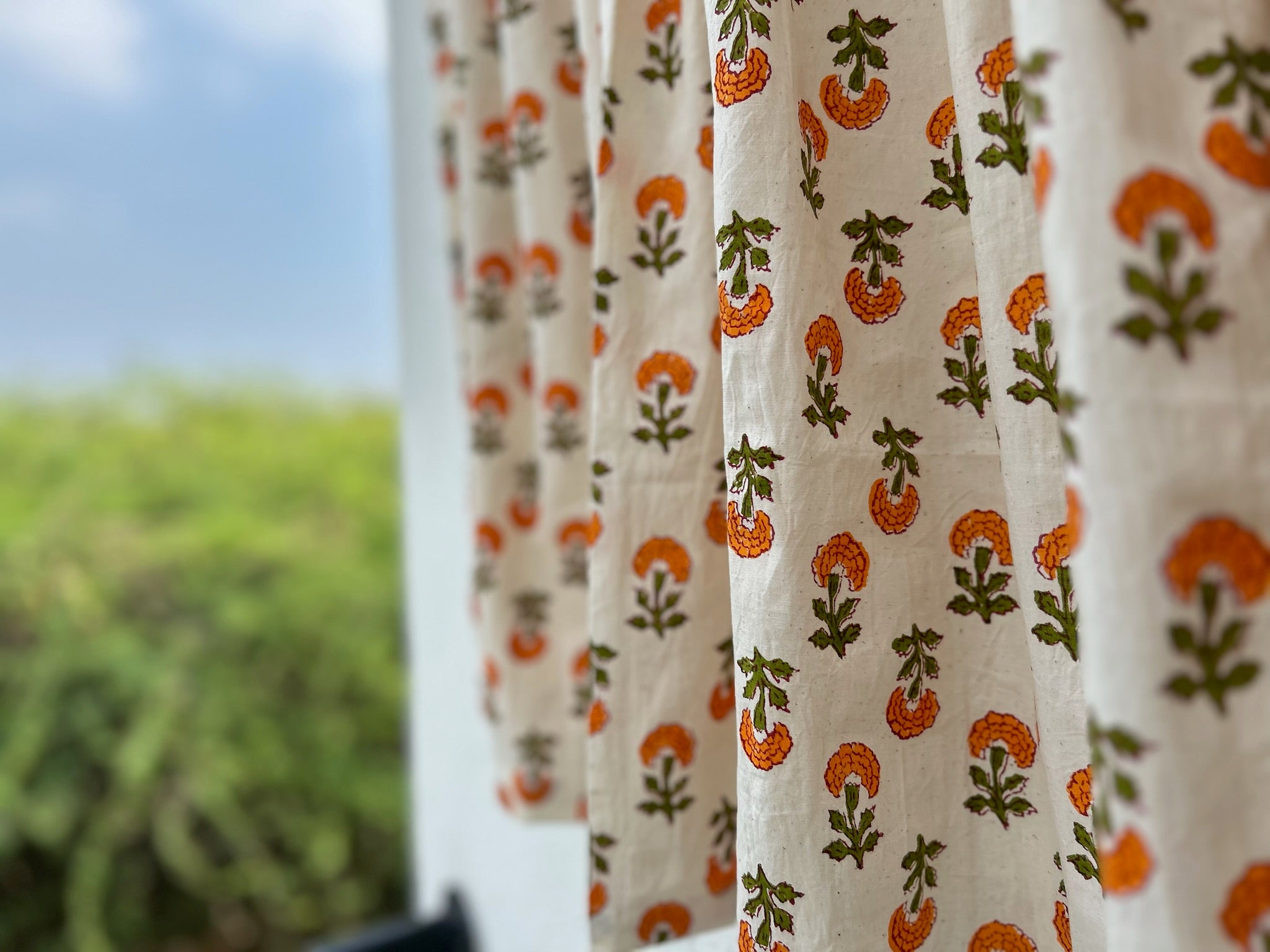Curtains with a floral pattern in front of a blurred outdoor background