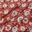 Floral patterned fabric with white flowers on a rust-colored background