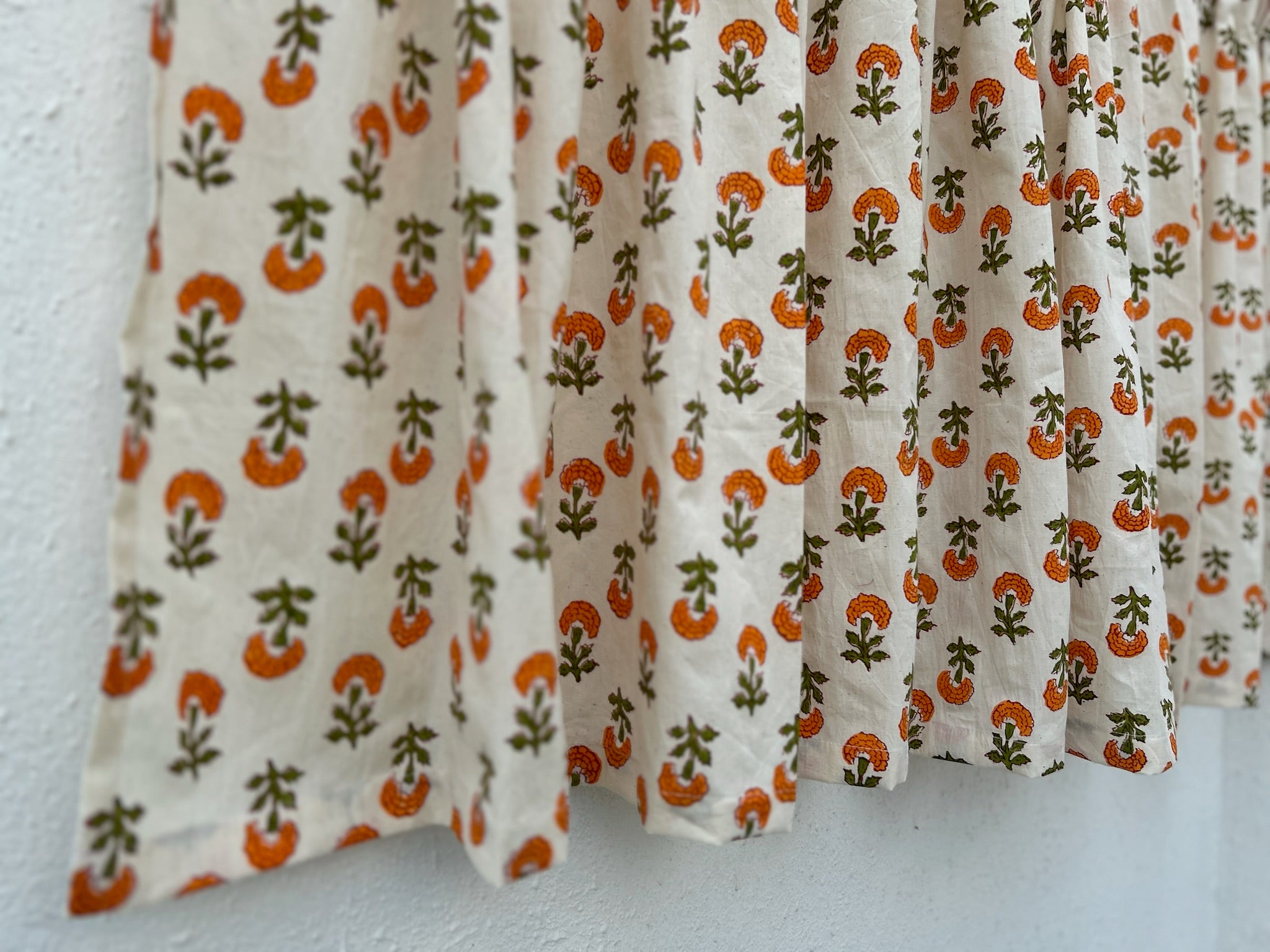 Curtain with orange and green floral pattern on a white background