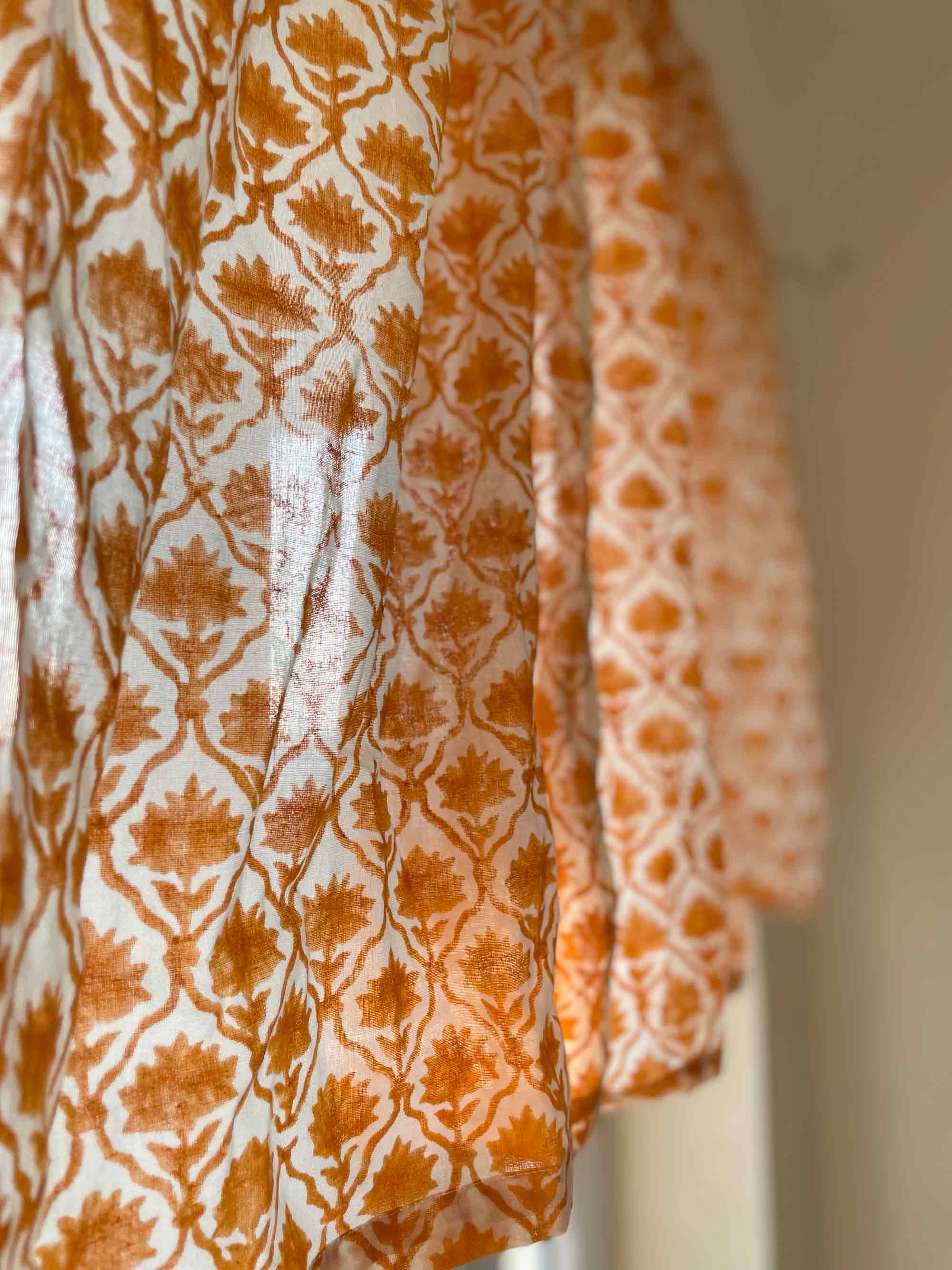 Two patterned fabrics hanging side by side with a neutral background