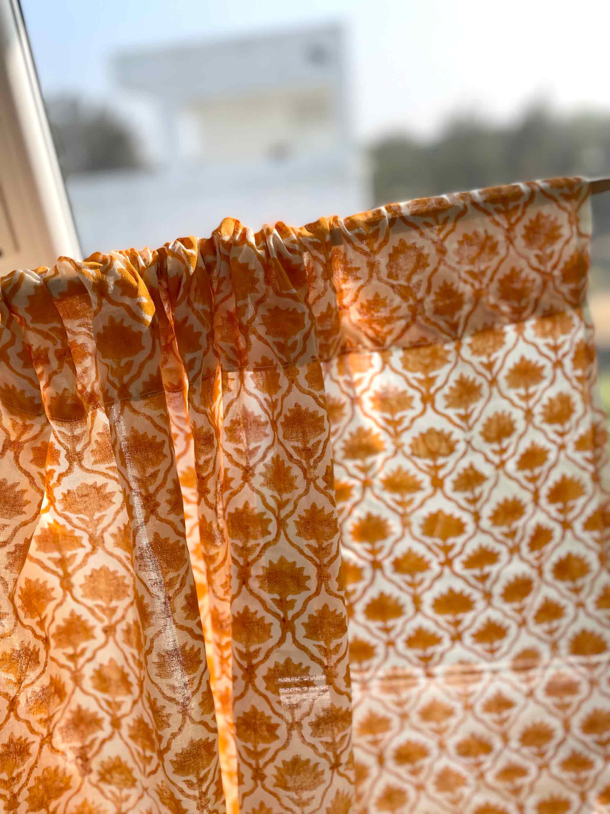 Orange and white patterned fabric draped over a surface with a blurred outdoor background.