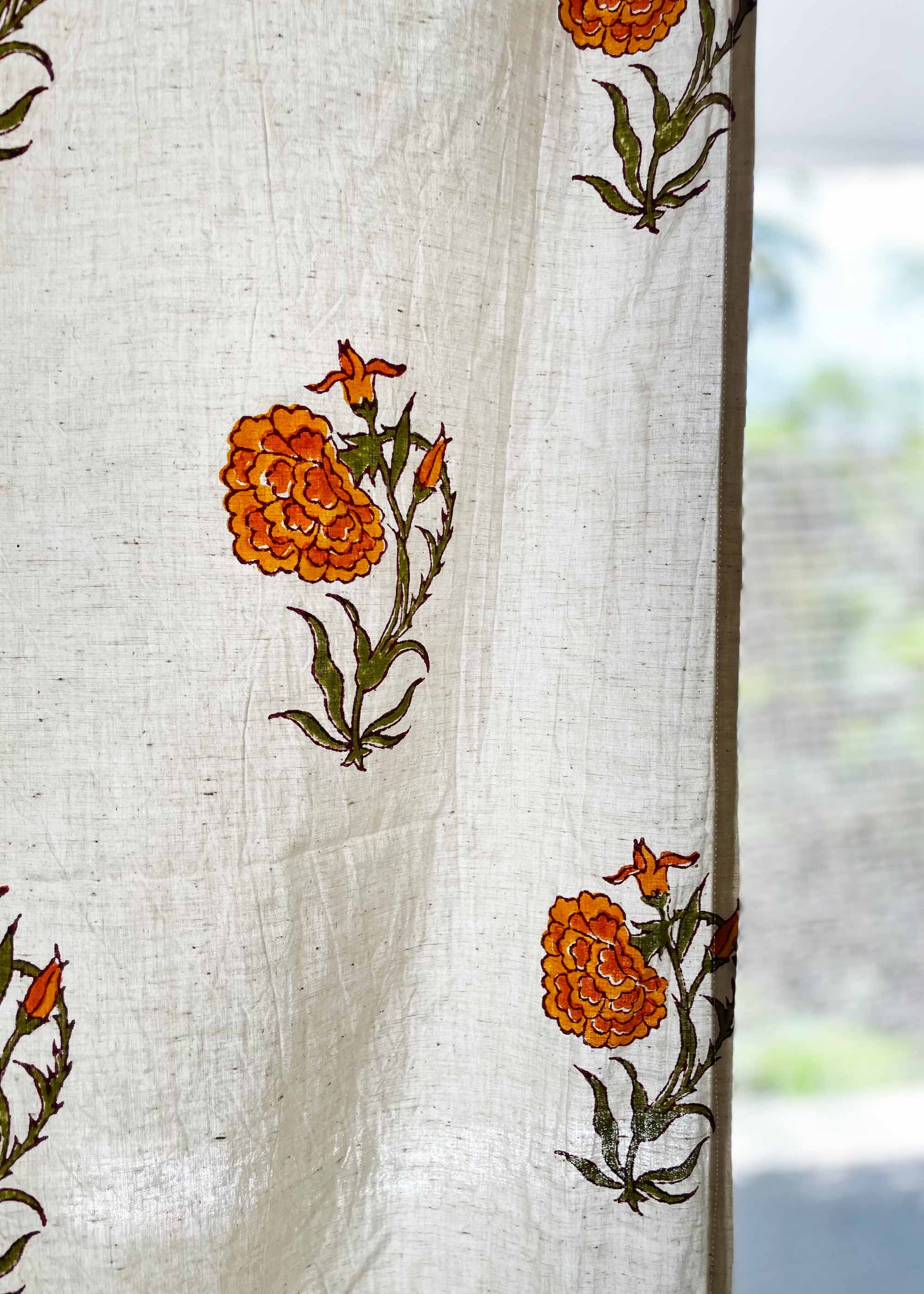 White fabric with orange floral patterns, possibly a curtain or cloth.