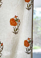 White fabric with orange floral patterns, possibly a curtain or cloth.