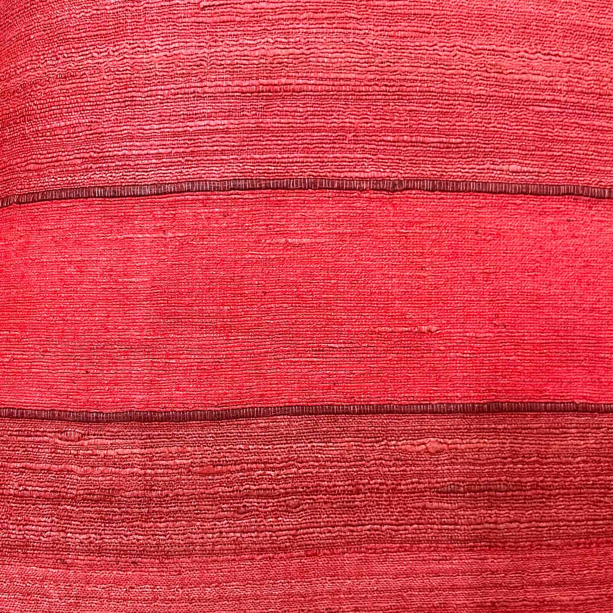 Close-up of red striped tussar silk pillow cover highlighting fine handloom stripes and organic silk slubs.