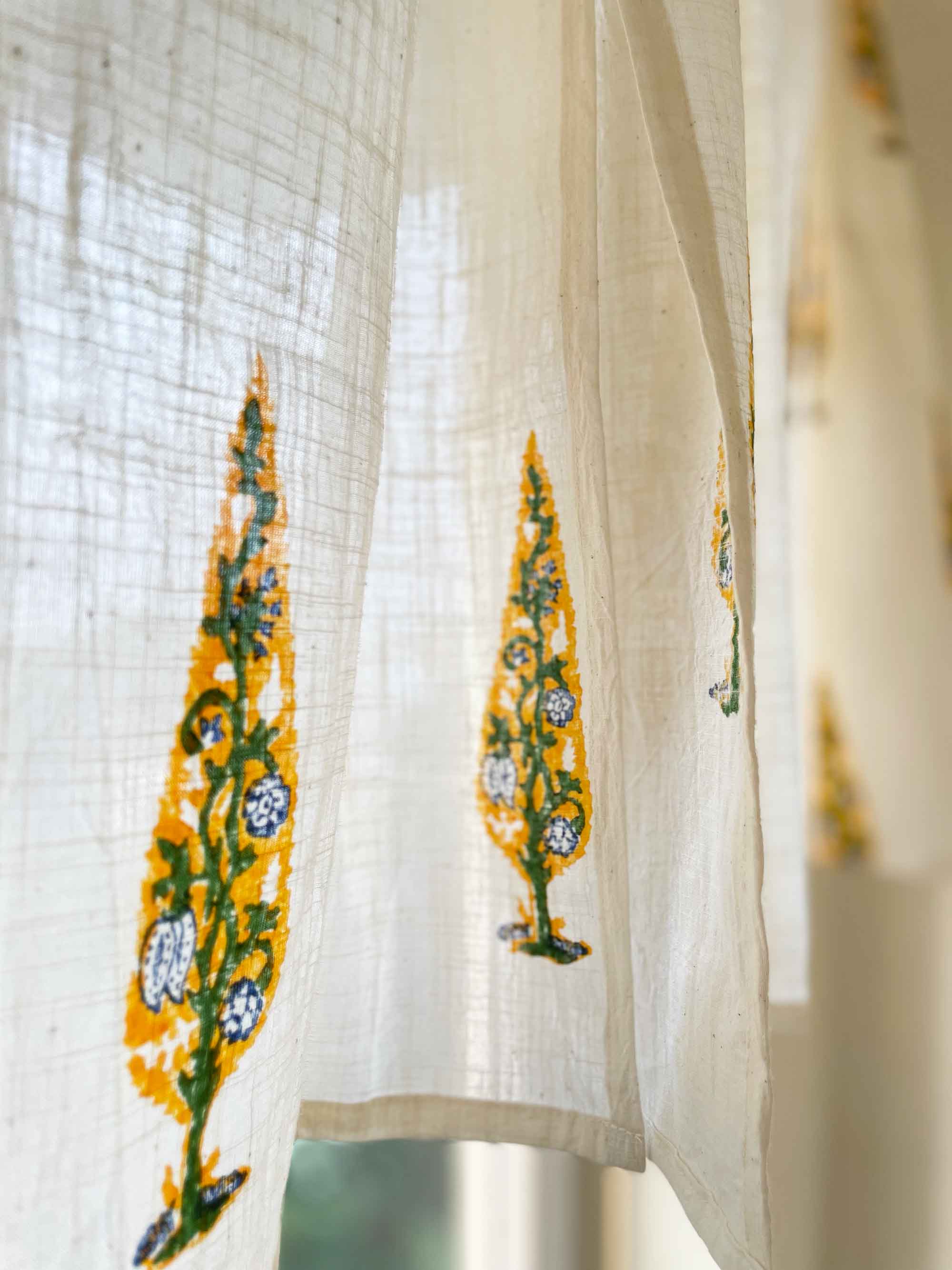Sheer curtain with embroidered yellow and green patterns on a blurred background