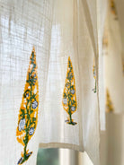 Sheer curtain with embroidered yellow and green patterns on a blurred background